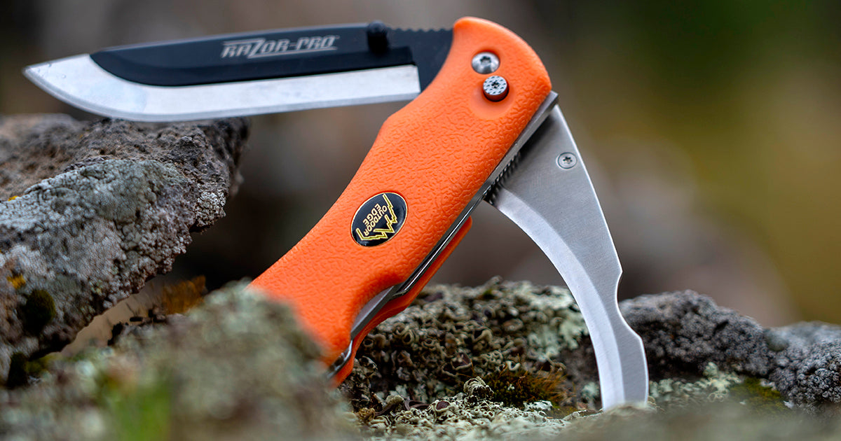 The orange-handled Outdoor Edge RazorPro, a double-blade folding knife, is shown with both its main drop-point blade and its signature gutting blade open and locked