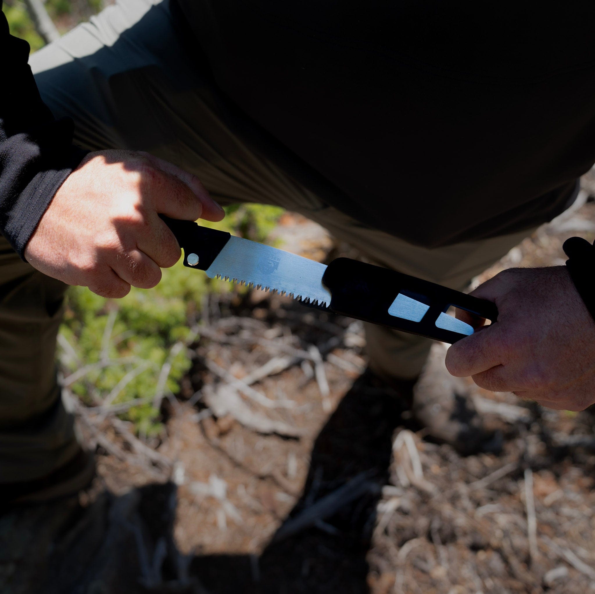 Person holding a saw outdoors with natural background