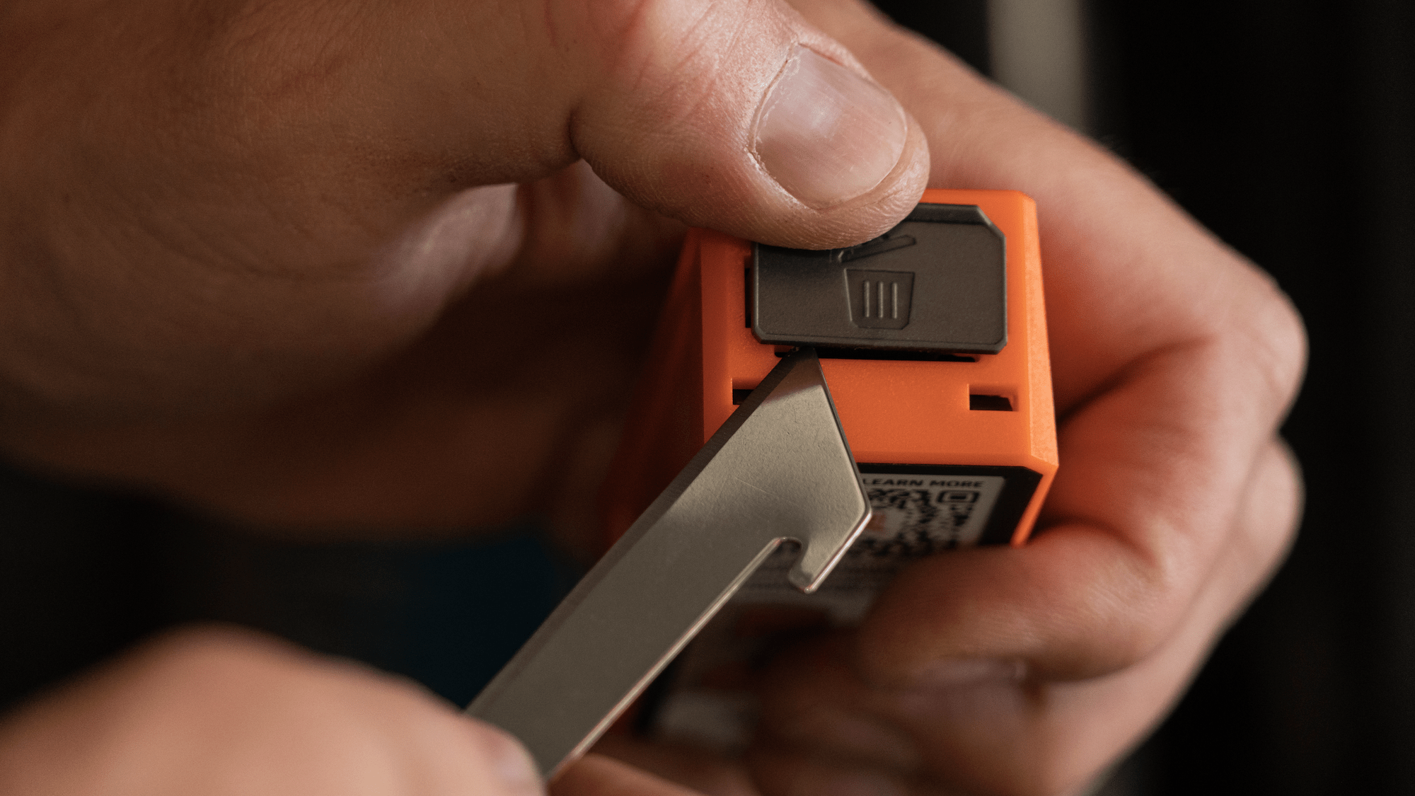 A person using an Outdoor Edge utility knife to cut open a cardboard box