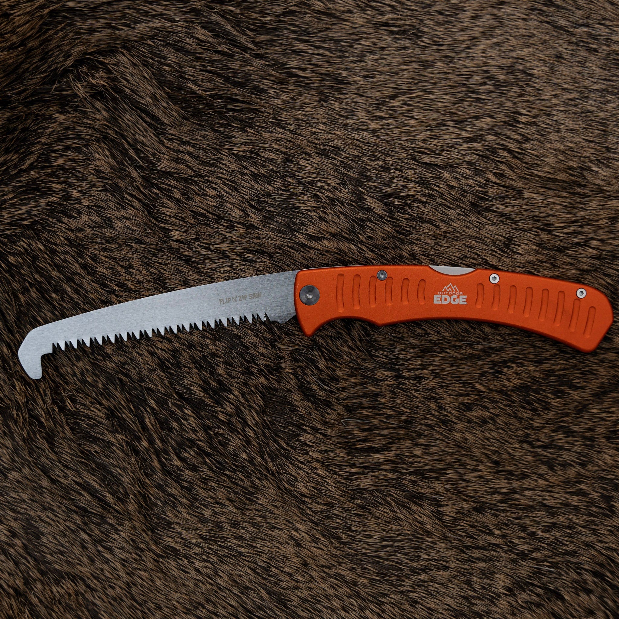 Folding saw with orange handle on a brown fur background