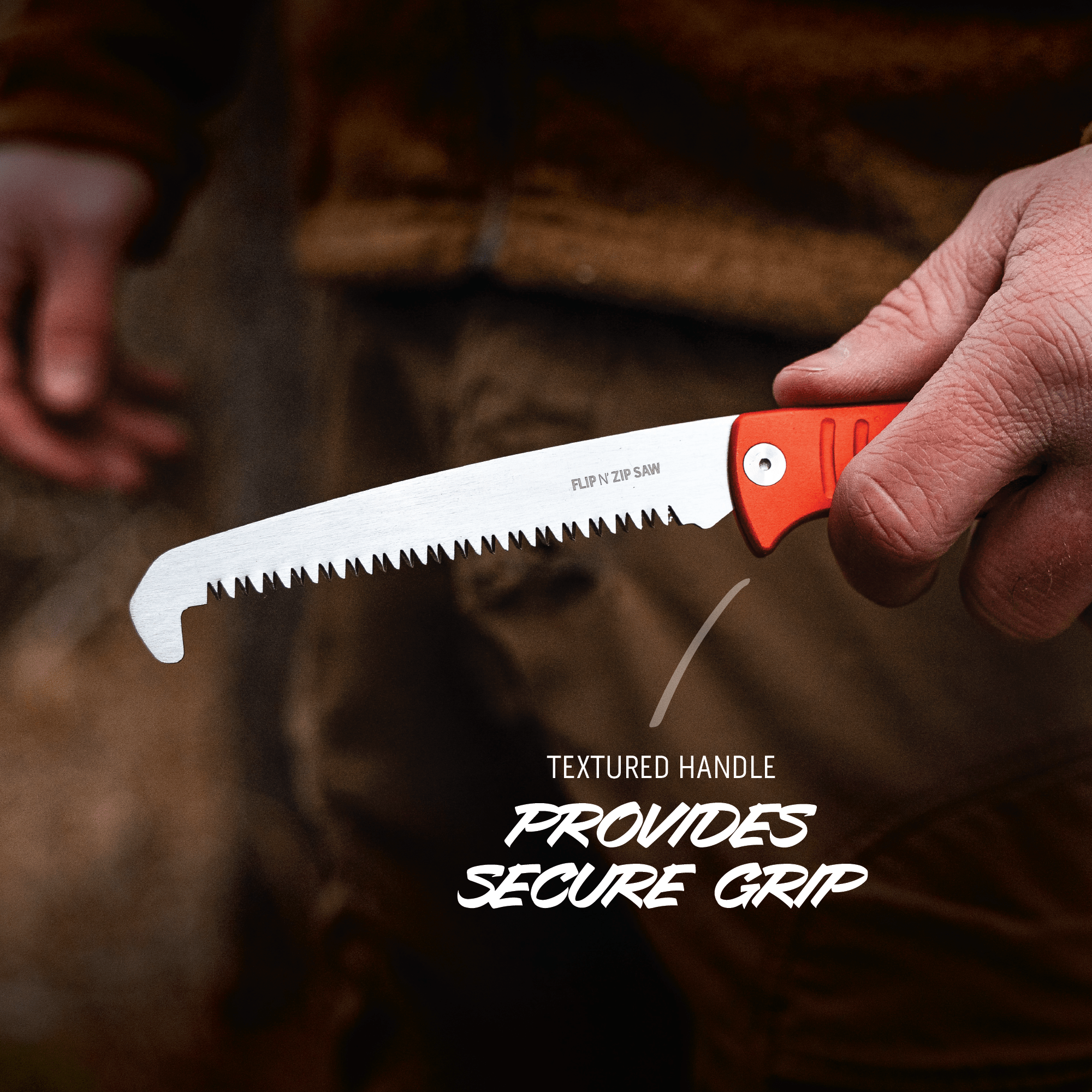 Hand holding a folding saw with a textured handle, blurred background