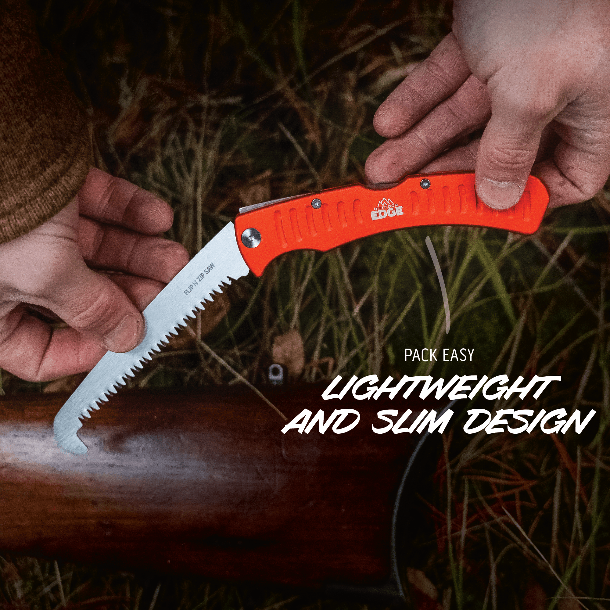 Orange folding saw held by hands with grass and wood background
