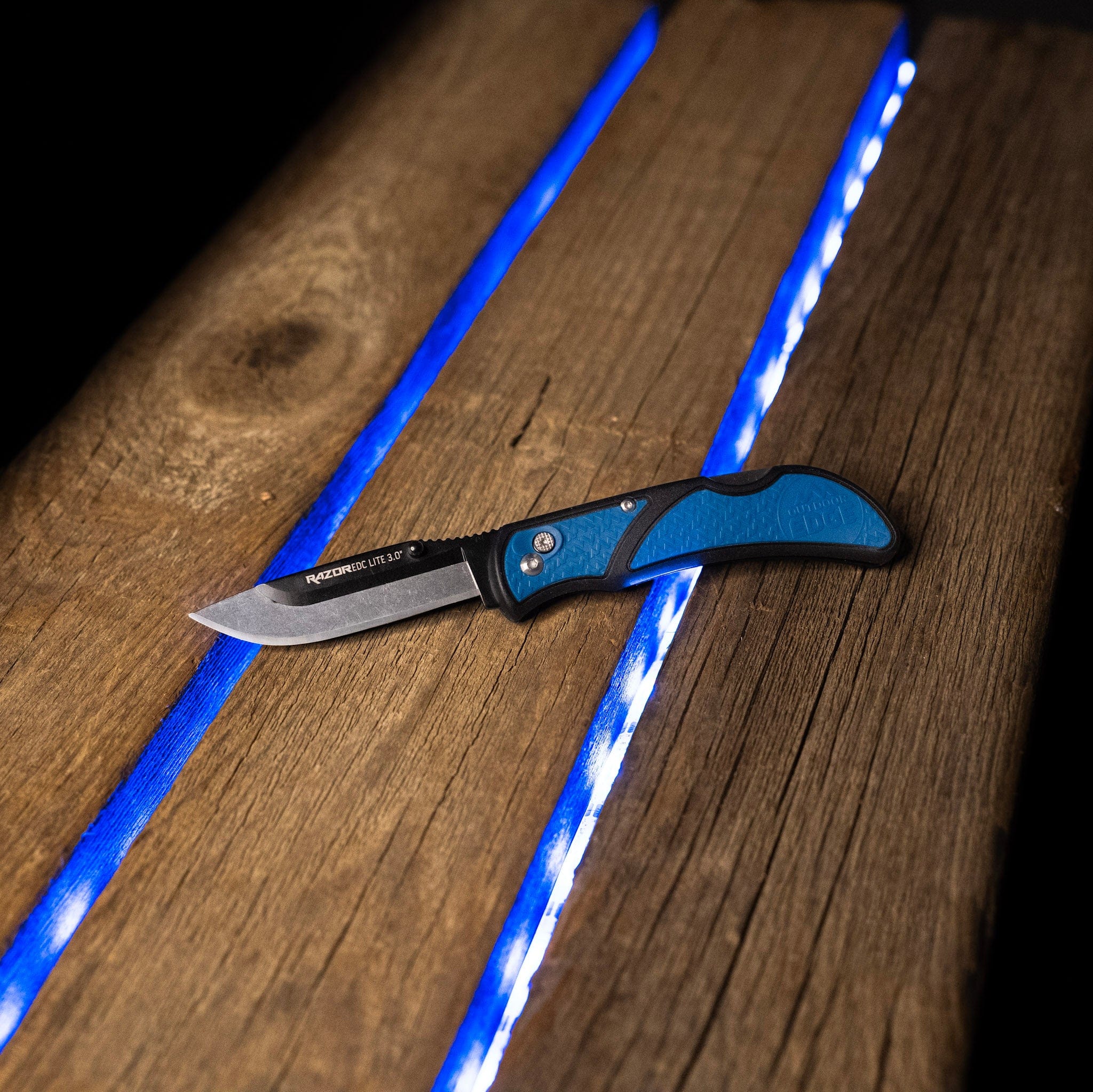 Blue pocket knife sitting on backlit wood