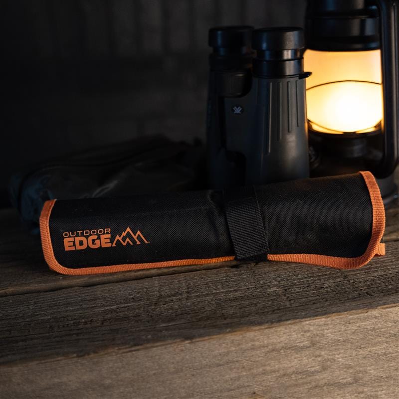 A black knife roll pack with 'Outdoor Edge' branding on a wooden surface.