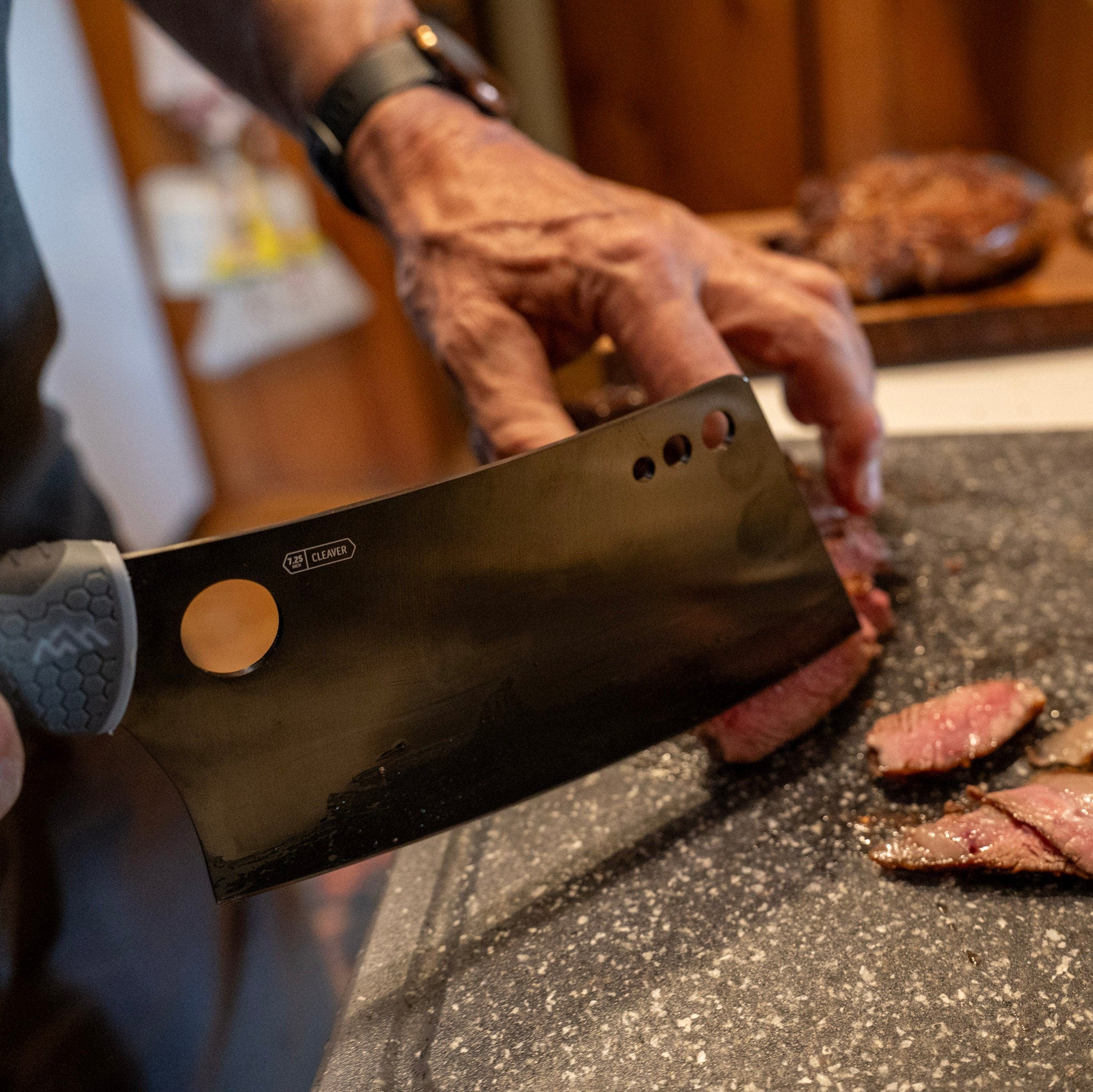 Person cutting meat with a cleaver on a cutting board