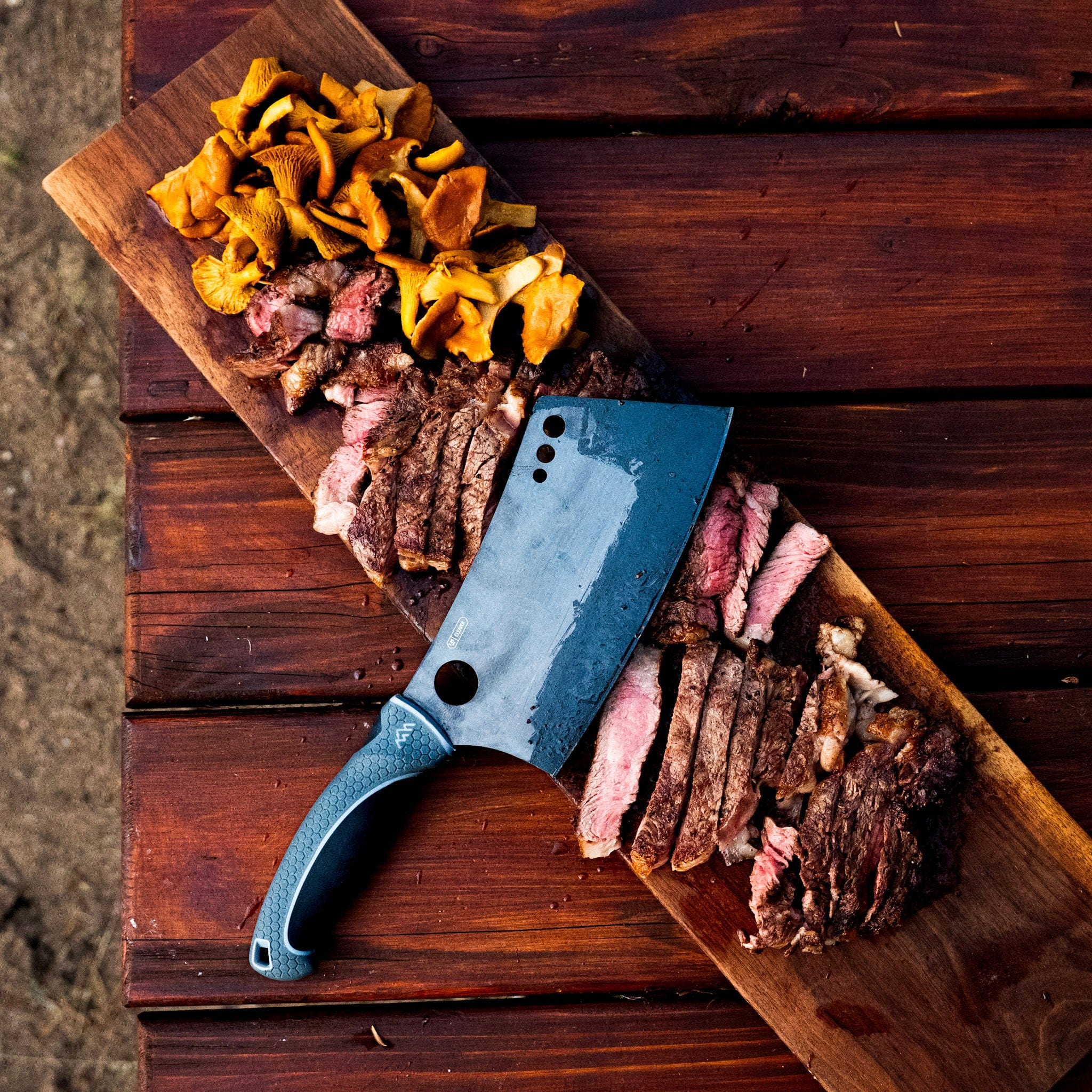 Wooden cutting board with sliced meats and a cleaver on a rustic wooden surface.