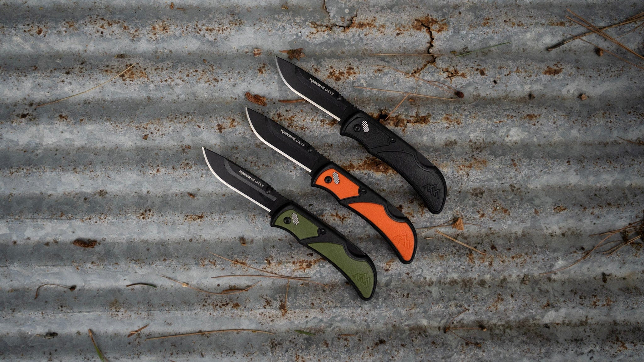 Three folding knives on a rusty metal surface