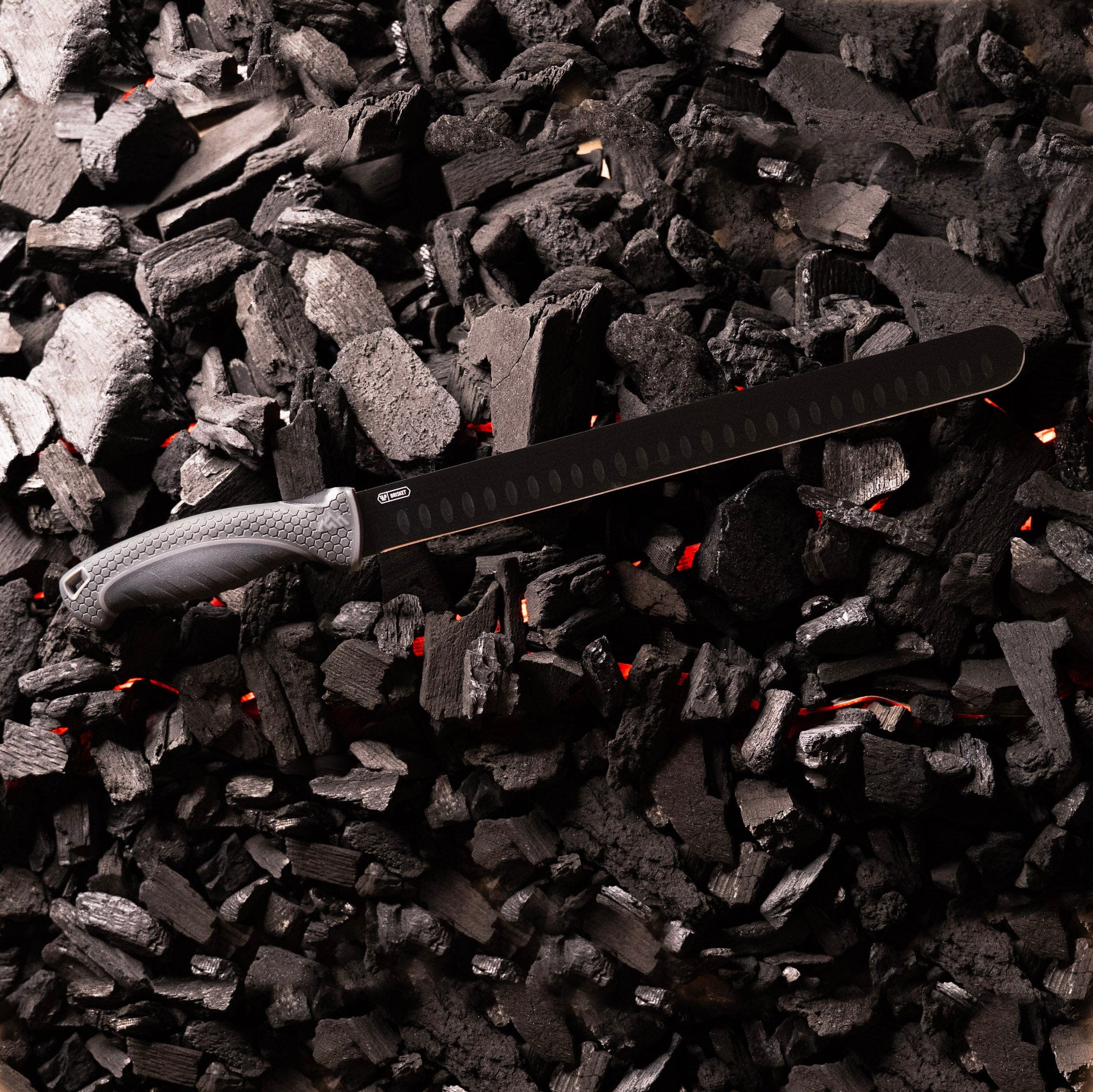 Brisket slicer knife sitting on glowing charcoal