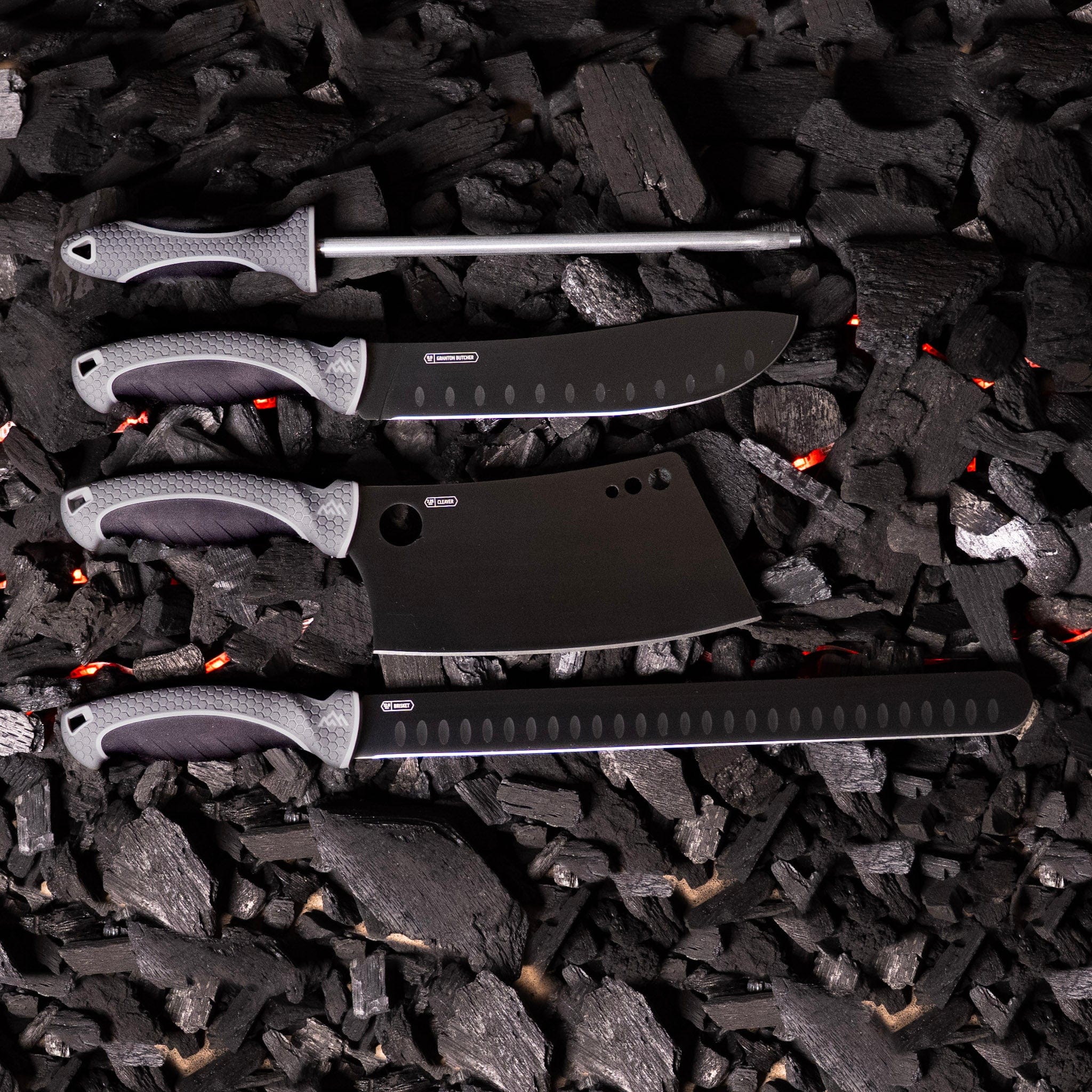 BBQ knife set with honing rod sitting on glowing charcoal