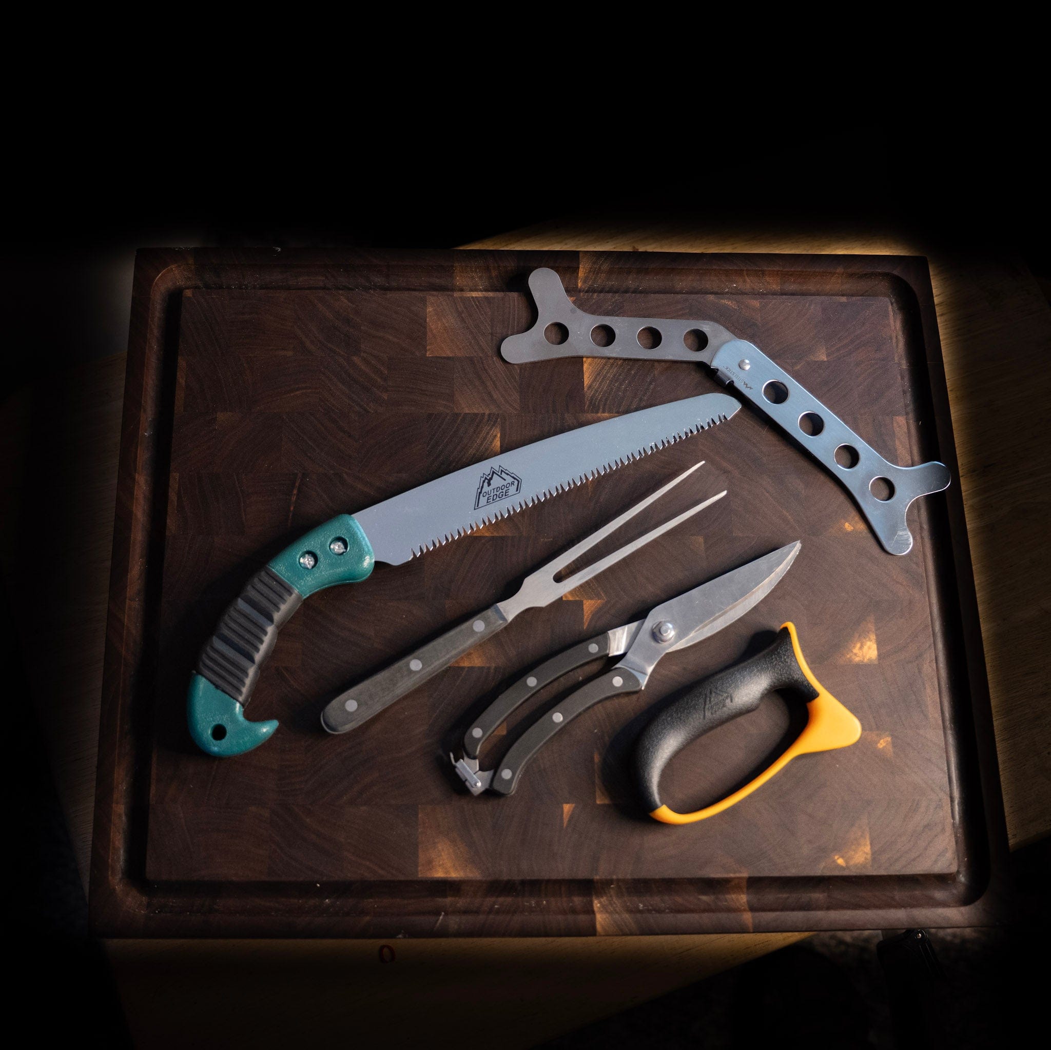 Set of game processing tools including a saw, pruners, and shears on a wooden surface.