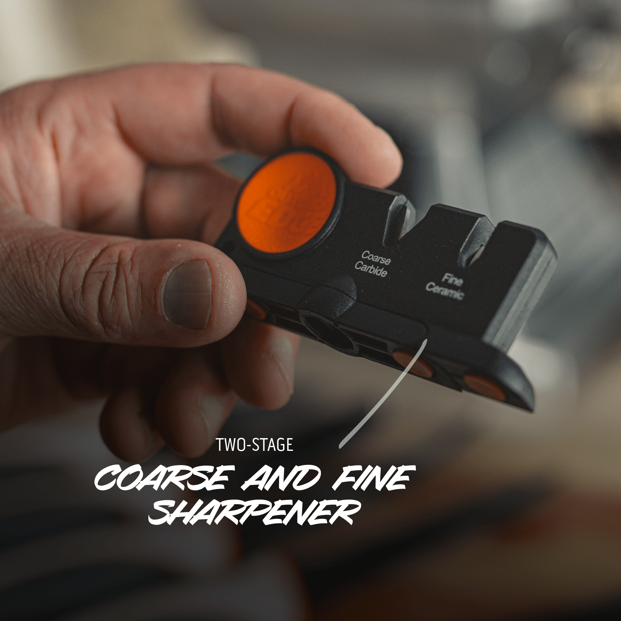 Hand holding a two-stage coarse and fine sharpener with an orange button.