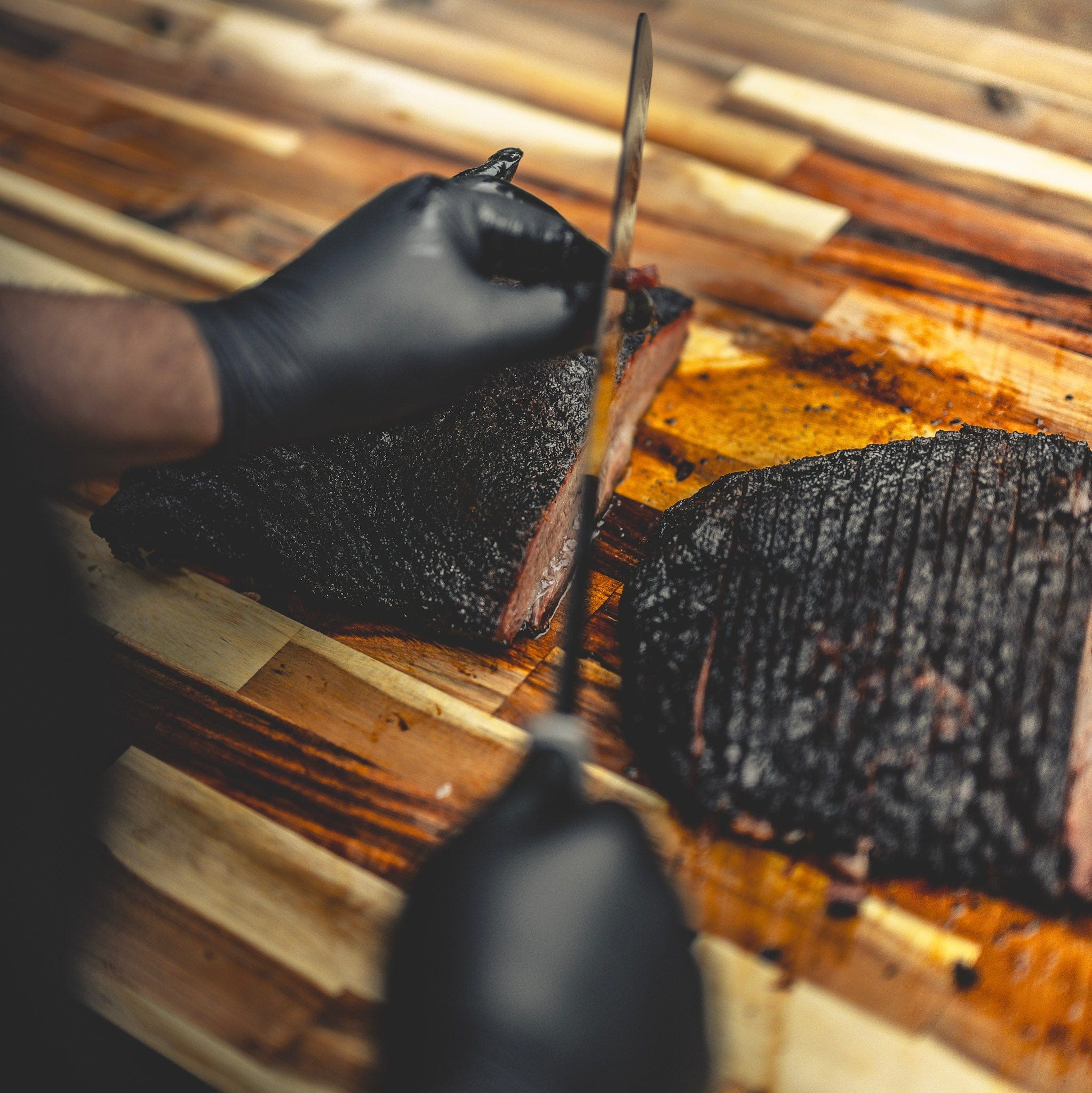 Brisket knife slicing brisket on a wooden cutting board