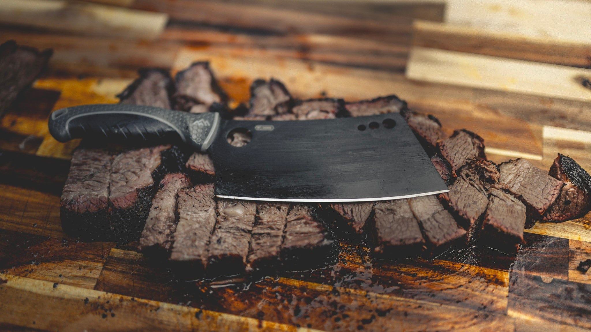 Meat cleaver on a wooden cutting board with sliced meat