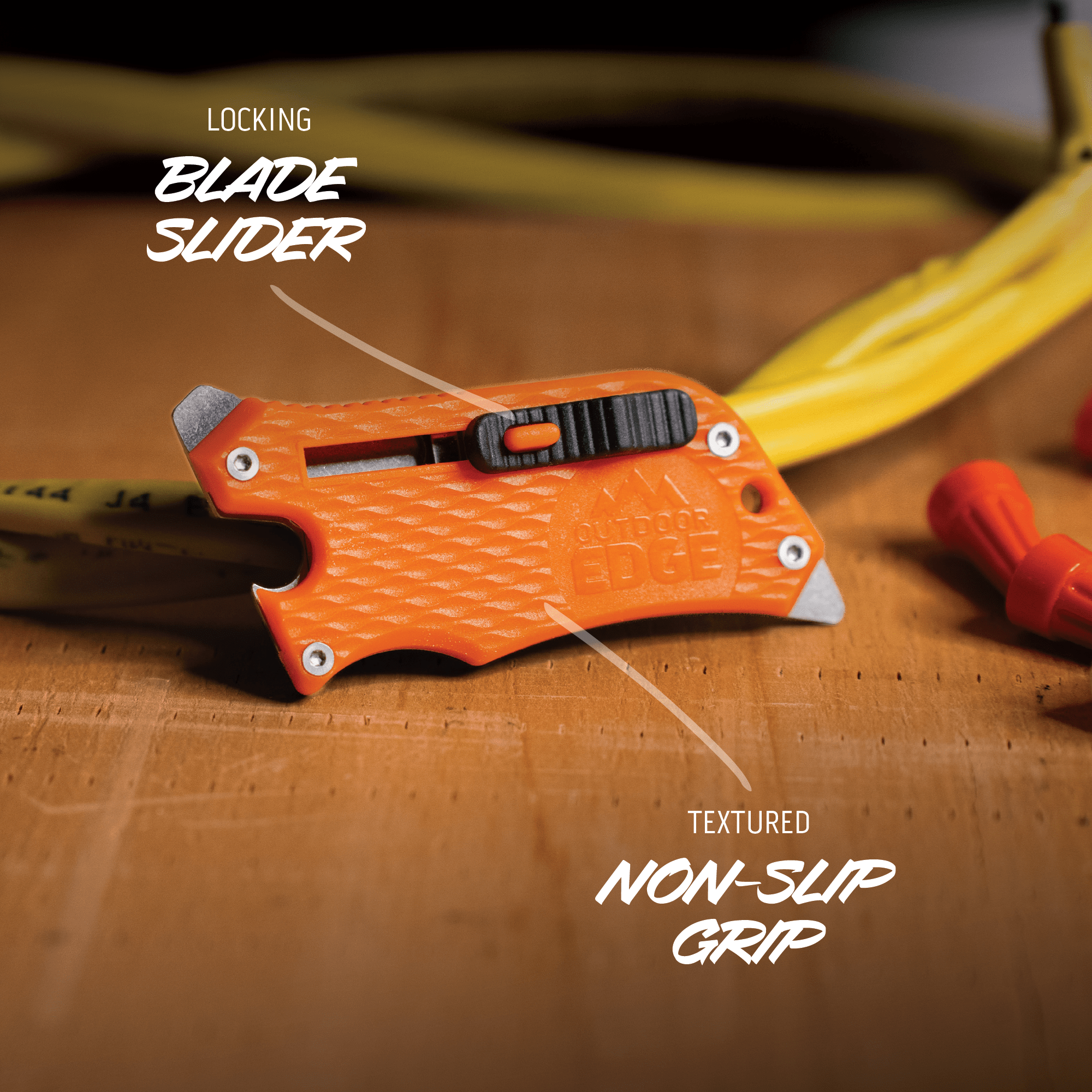 Orange utility knife with text highlighting features on a wooden surface