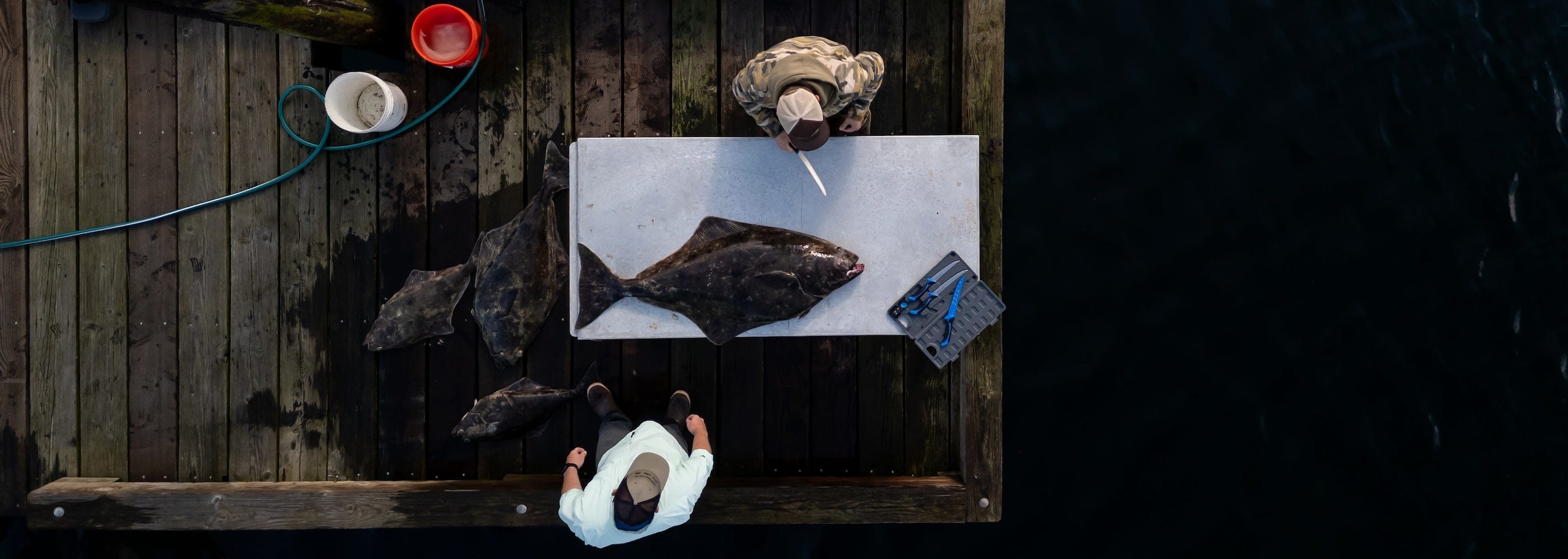 A large northern pike lying on a boat deck next to the 9.5-inch ReelFlex fillet knife and its blue sheath