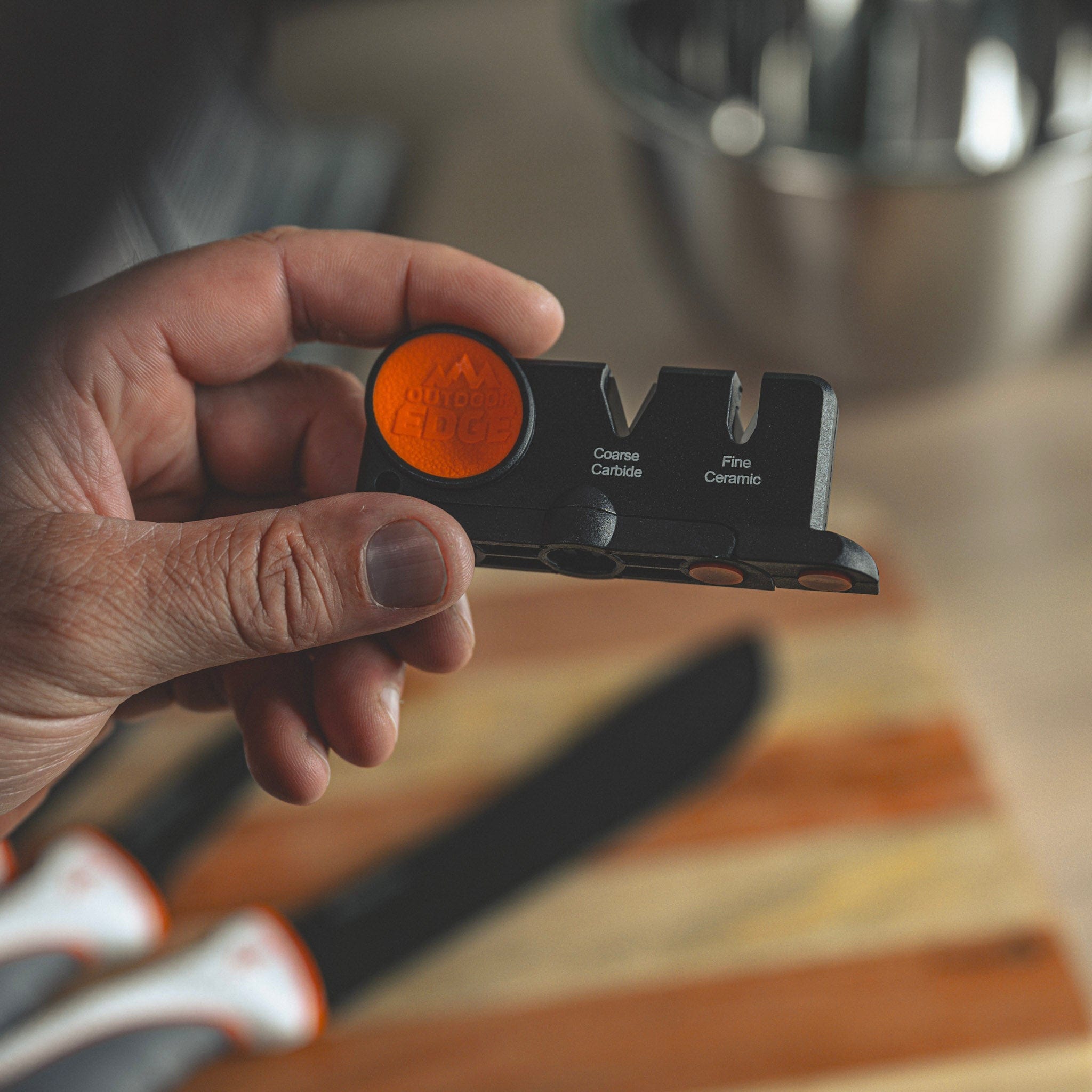 Hand holding a knife sharpener with a blurred background