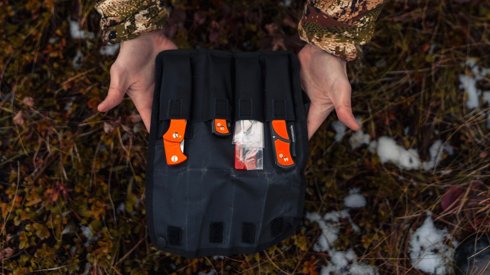 A hunter holding a roll pack of various Outdoor Edge knvies