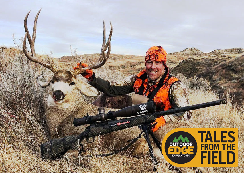  A hunter in blaze orange and camouflage smiles while posing with a large harvested mule deer and his rifle in a dry, brushy landscape, with the "Tales from the Field" logo overlaid