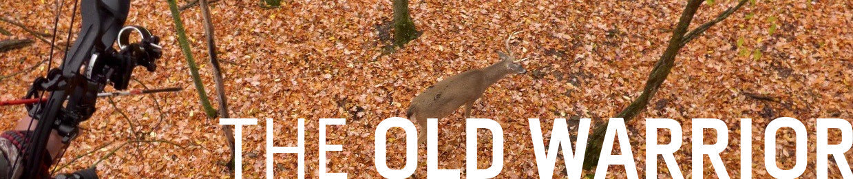 A very large, mature whitetail buck, referred to as 'The Old Warrior,' standing in the woods
