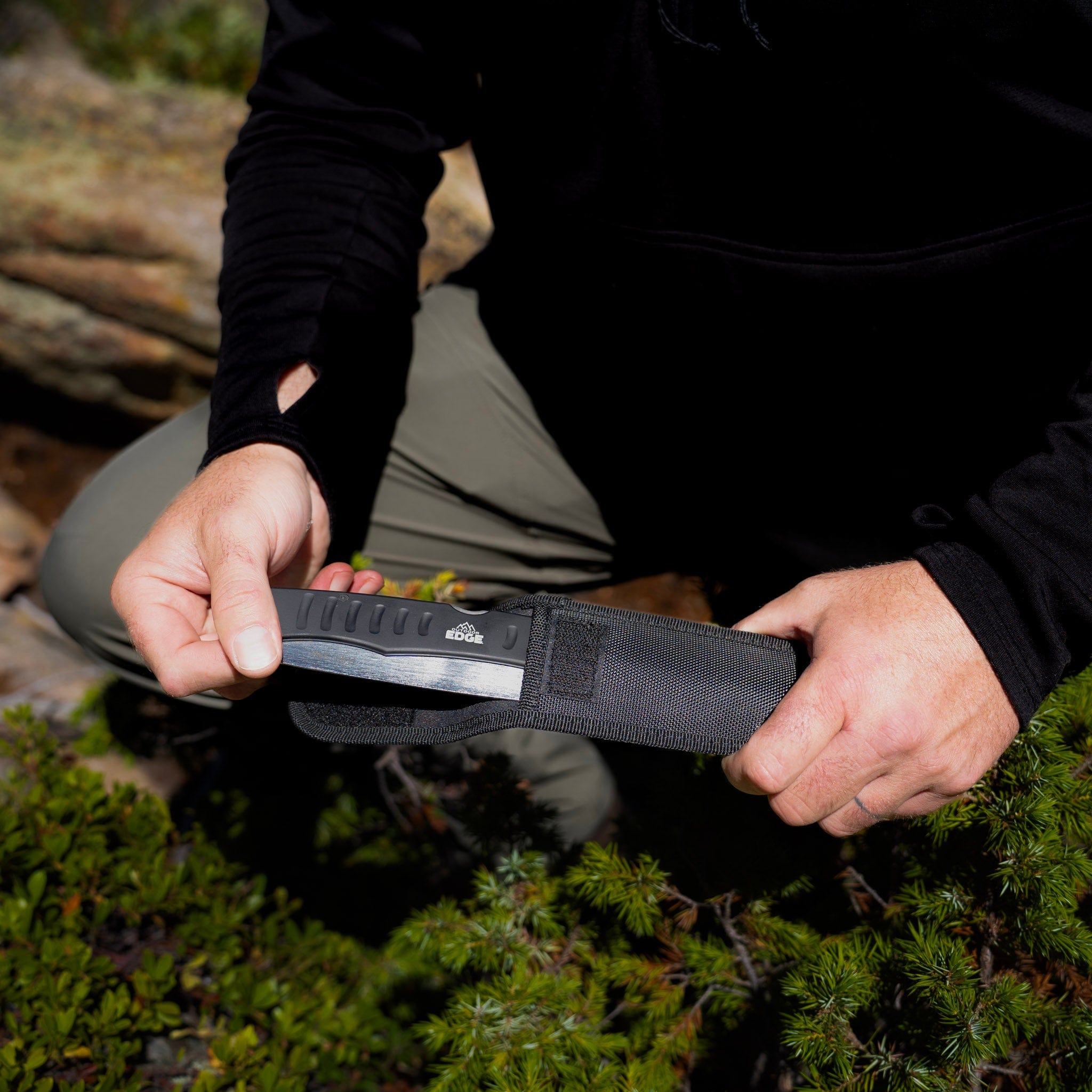 Person holding a saw with a sheath in a forest setting