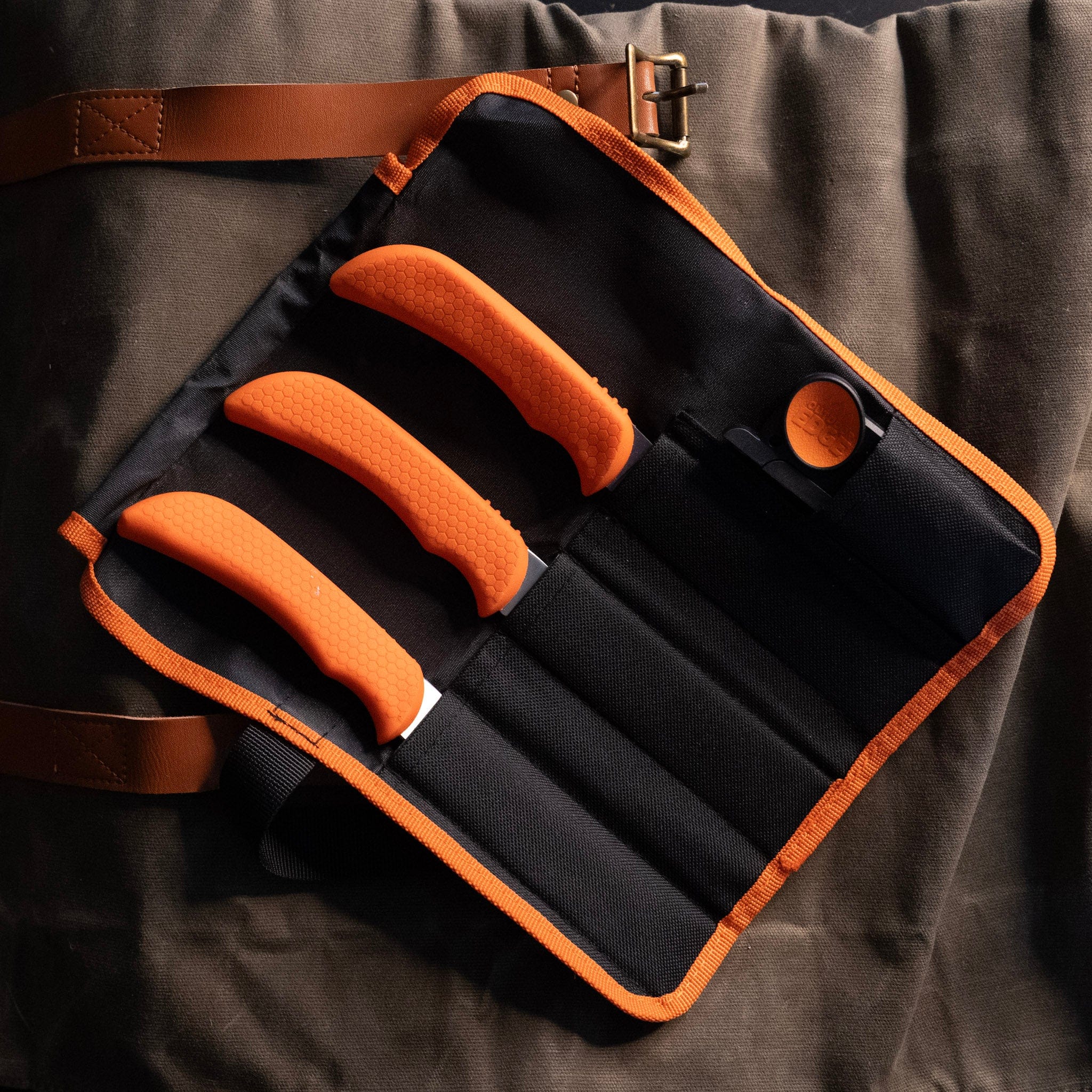 3 orange handled knives in a black nylon roll pack