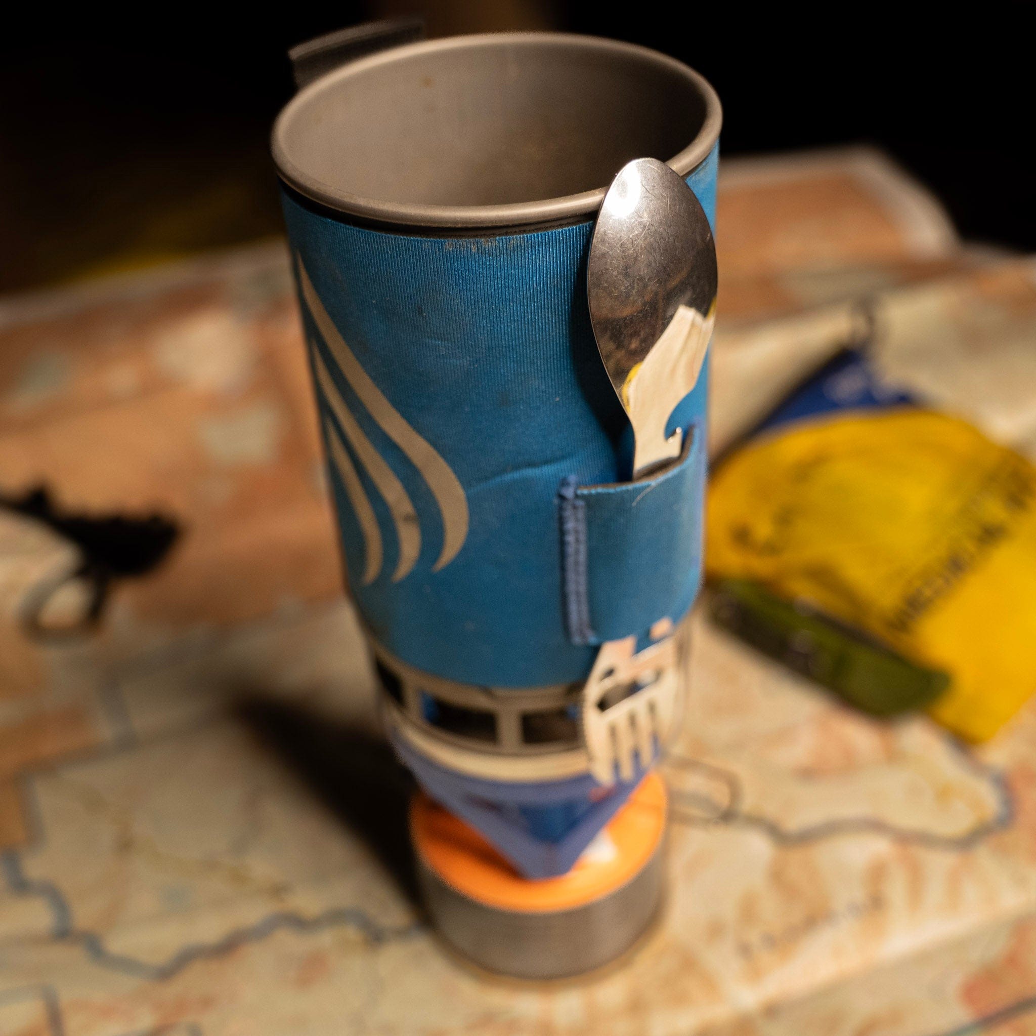 Blue insulated mug with spoon holder on a map