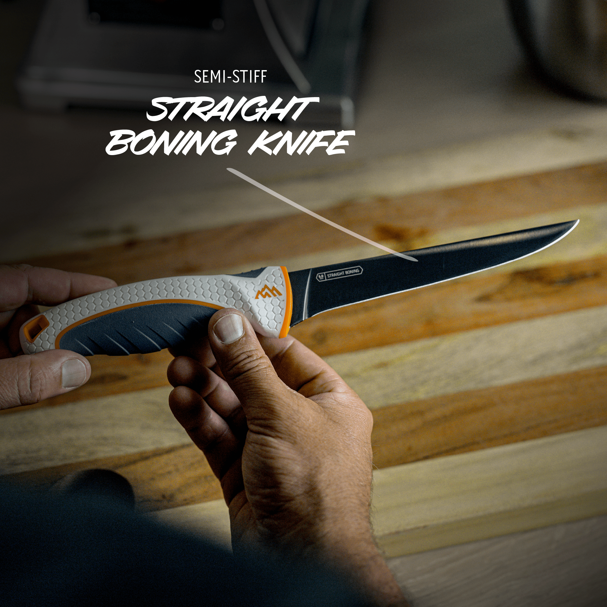 Hand holding a semi-stiff straight boning knife on a wooden surface