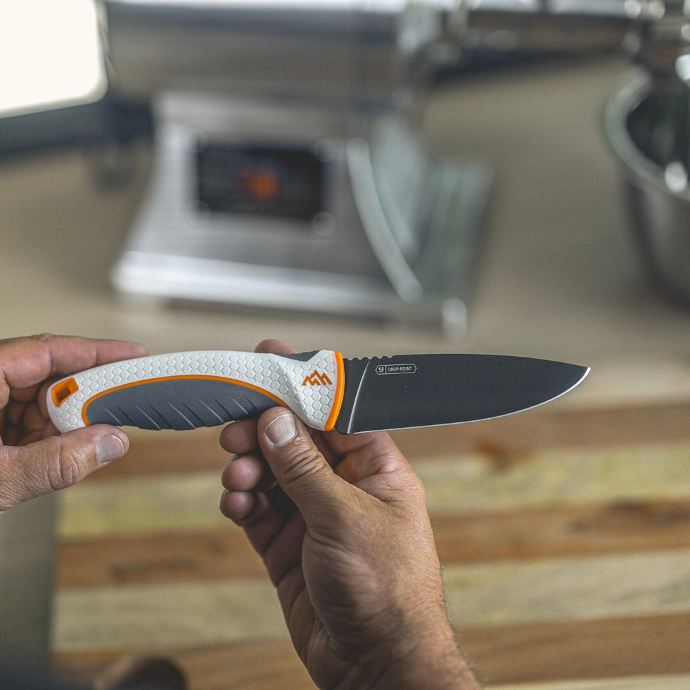 Hand holding a knife with a blurred kitchen background