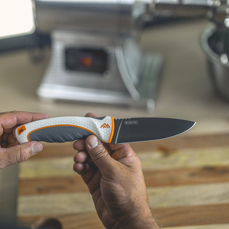 Hand holding a knife with a blurred kitchen background