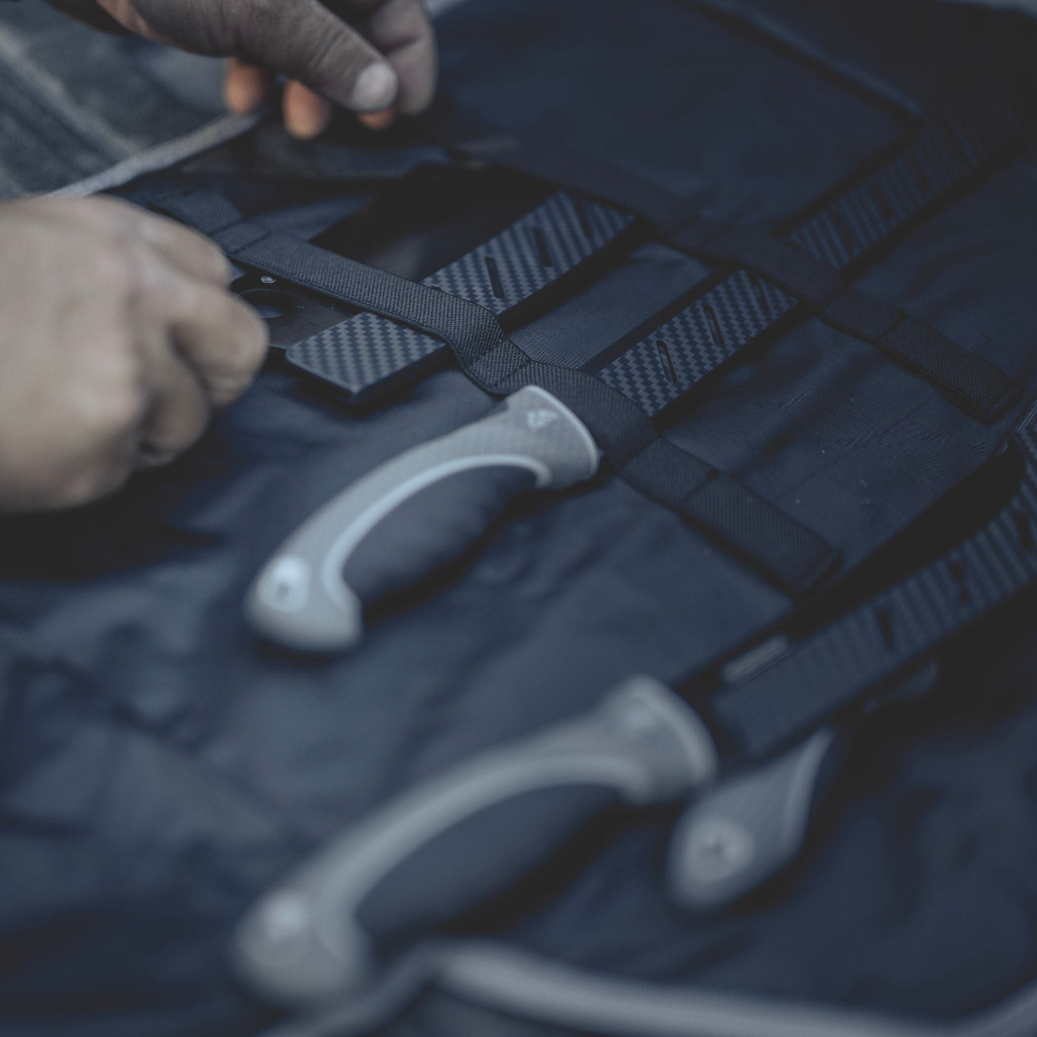 Close-up of hands adjusting straps on a bag with a blurred background