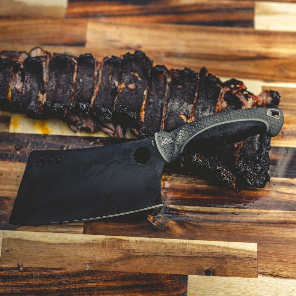 Black cleaver knife on a wooden surface with grilled meat in the background