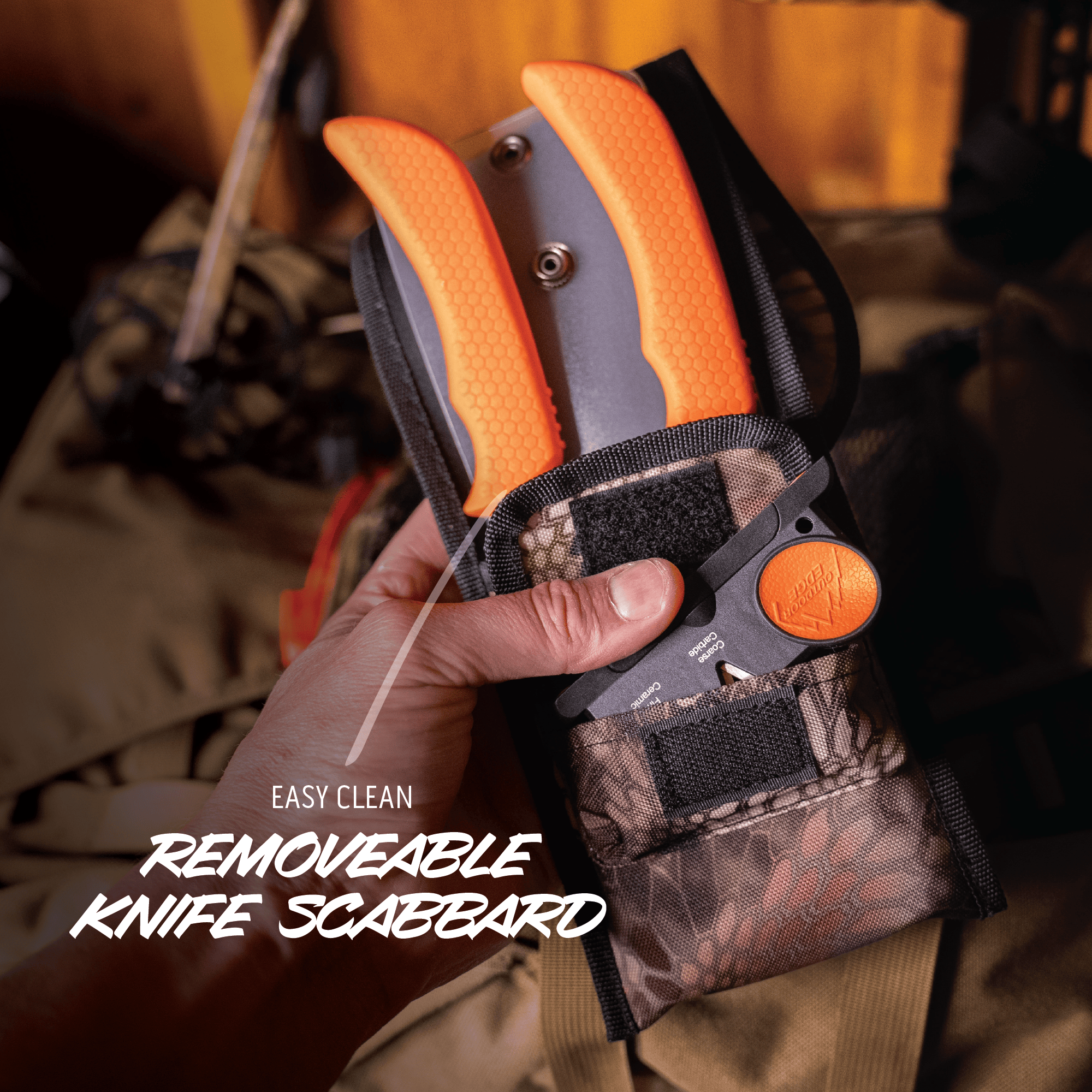 Hand holding a knife with an orange handle and camouflage sheath, with text 'Easy Clean Removeable Knife Scabbard'.