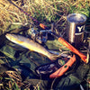 Outdoor Edge Field Bone Deboning and Fillet Knife in the grass next to a trout to be filleted