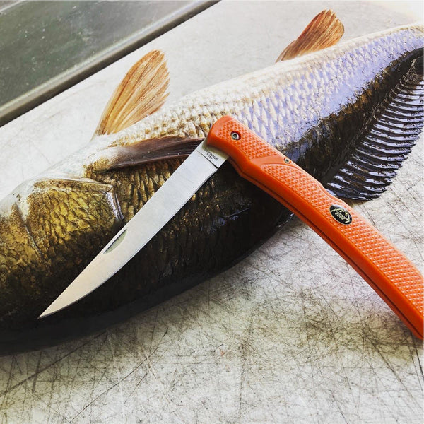 Outdoor Edge Field Bone Deboning and Fillet Knife laying on a red fish on fillet board